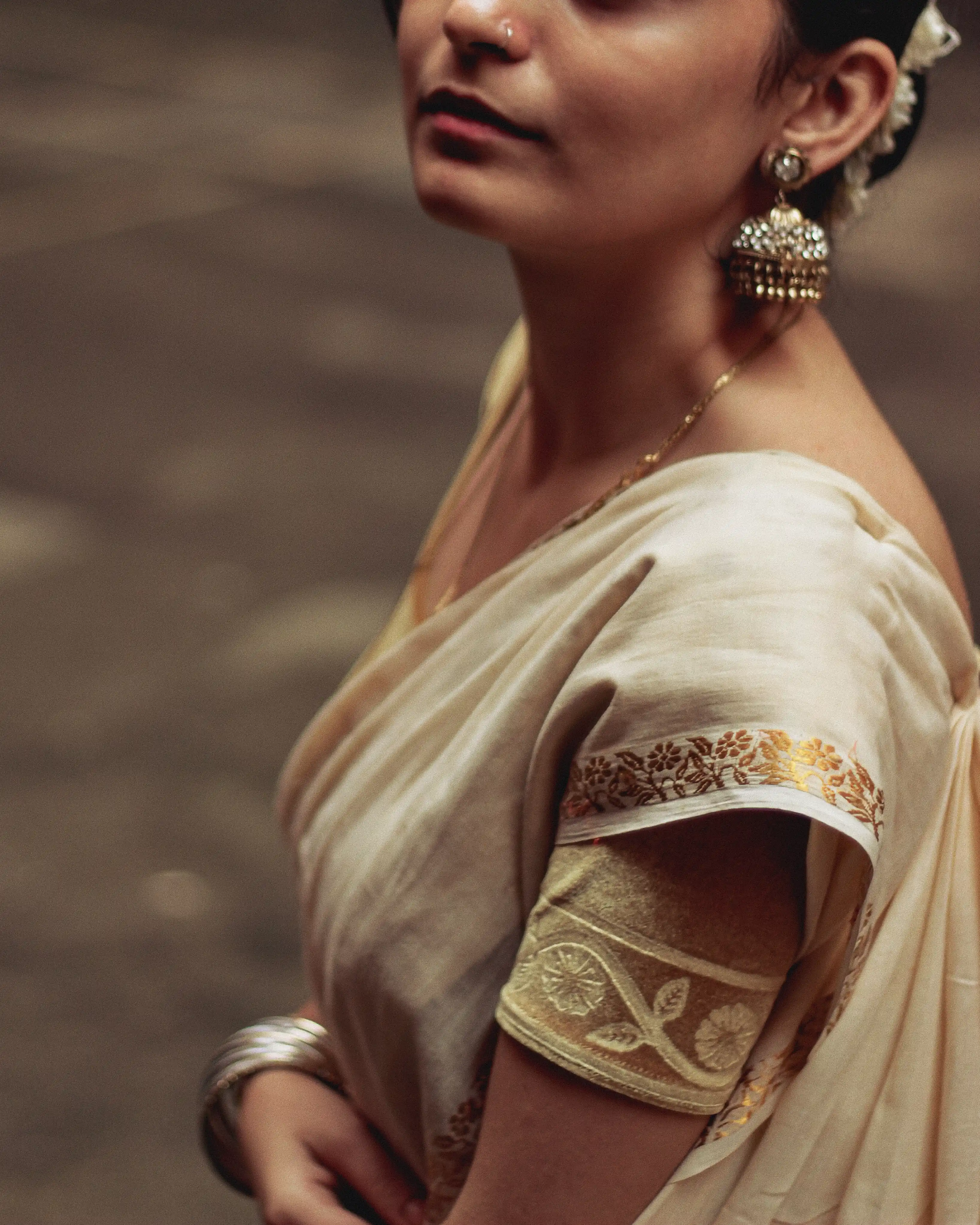 a woman wearing jhumka earrings and an Onam saree