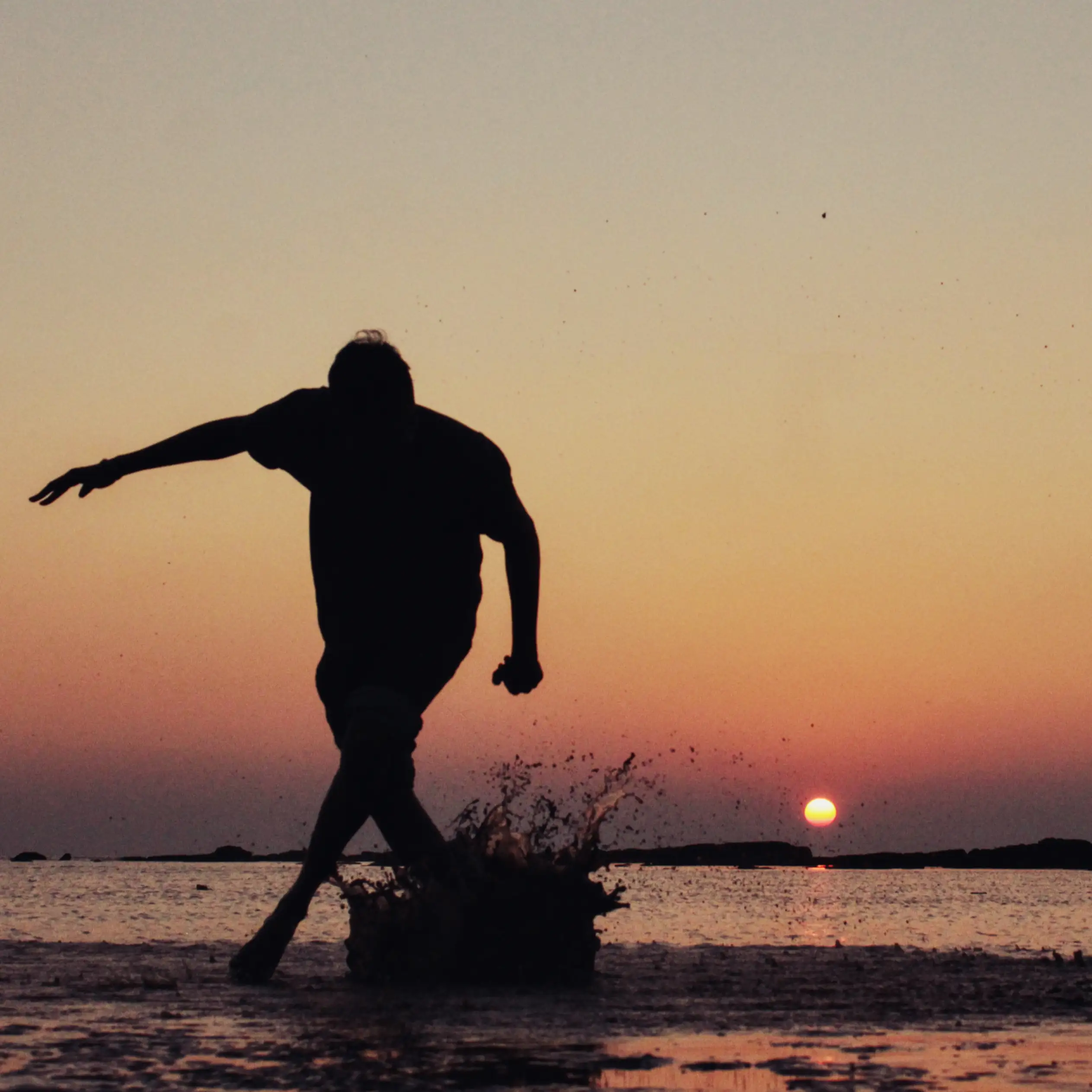 silhouette of a man kicking down on wet sand on Uttan beach