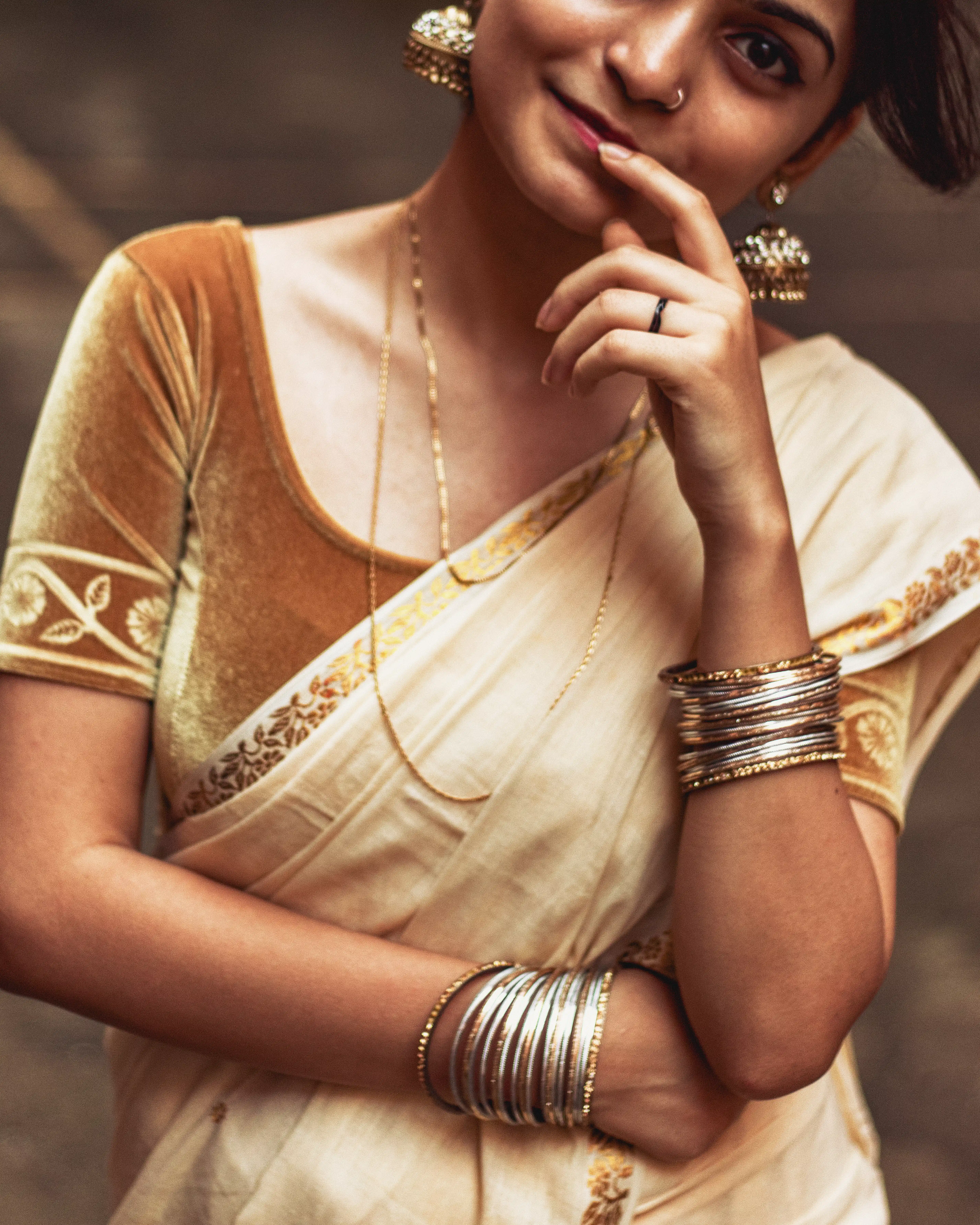 a girl wearing jhumka earrings and a traditional Onam saree