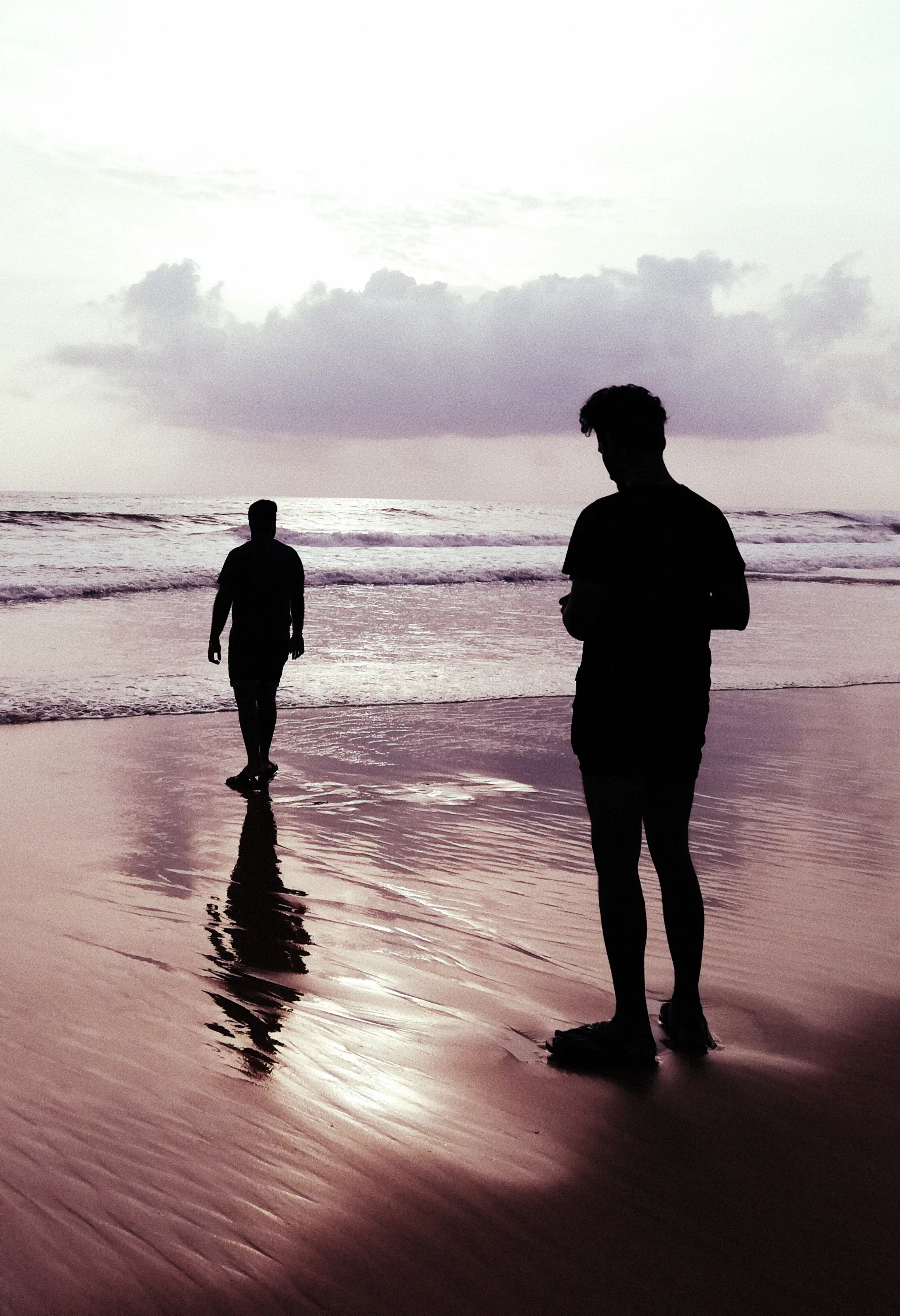 silhouettes of two men standing on the sands of Tivai Vaddo beach in Goa