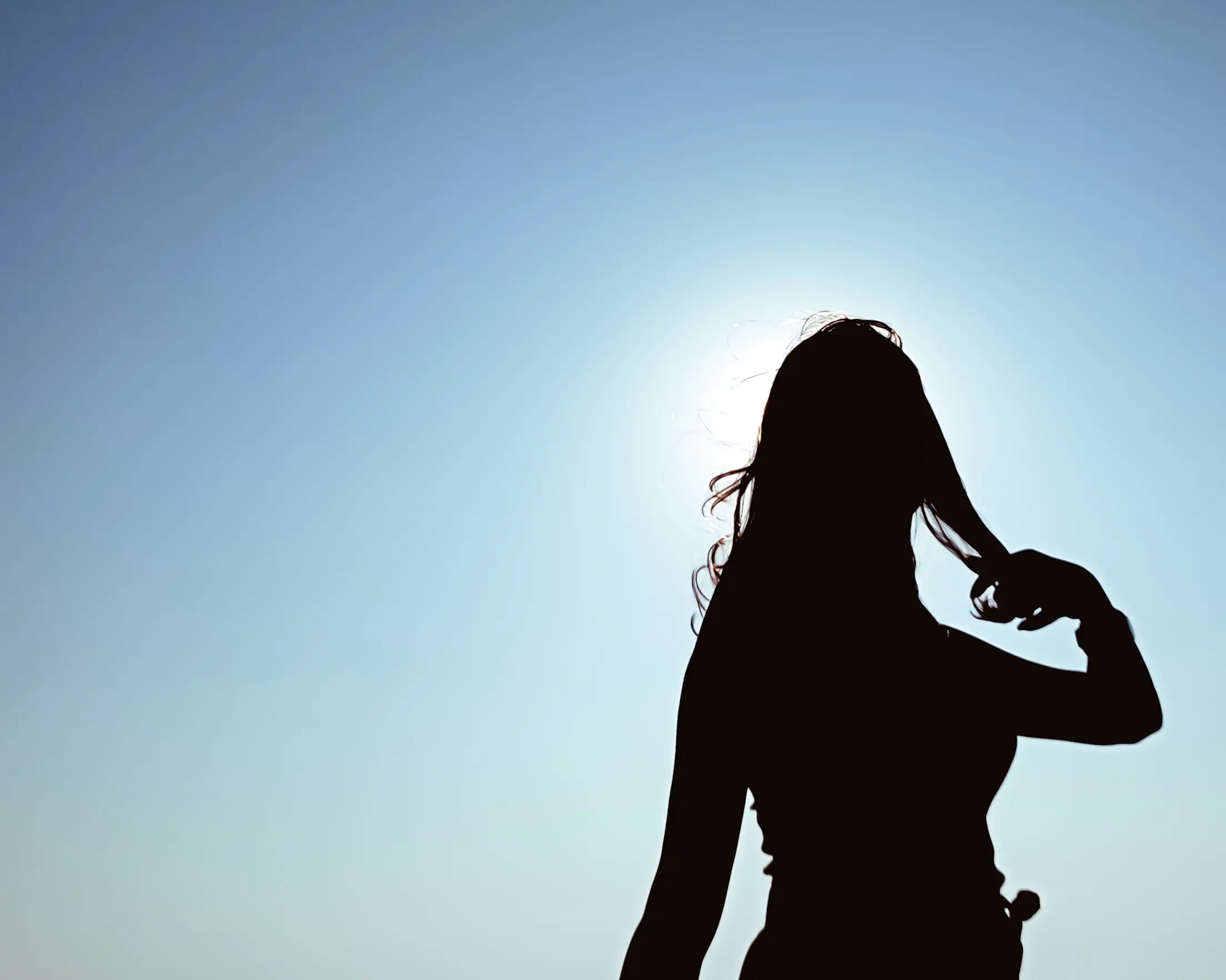 silhouette of a woman while she brushes her hair