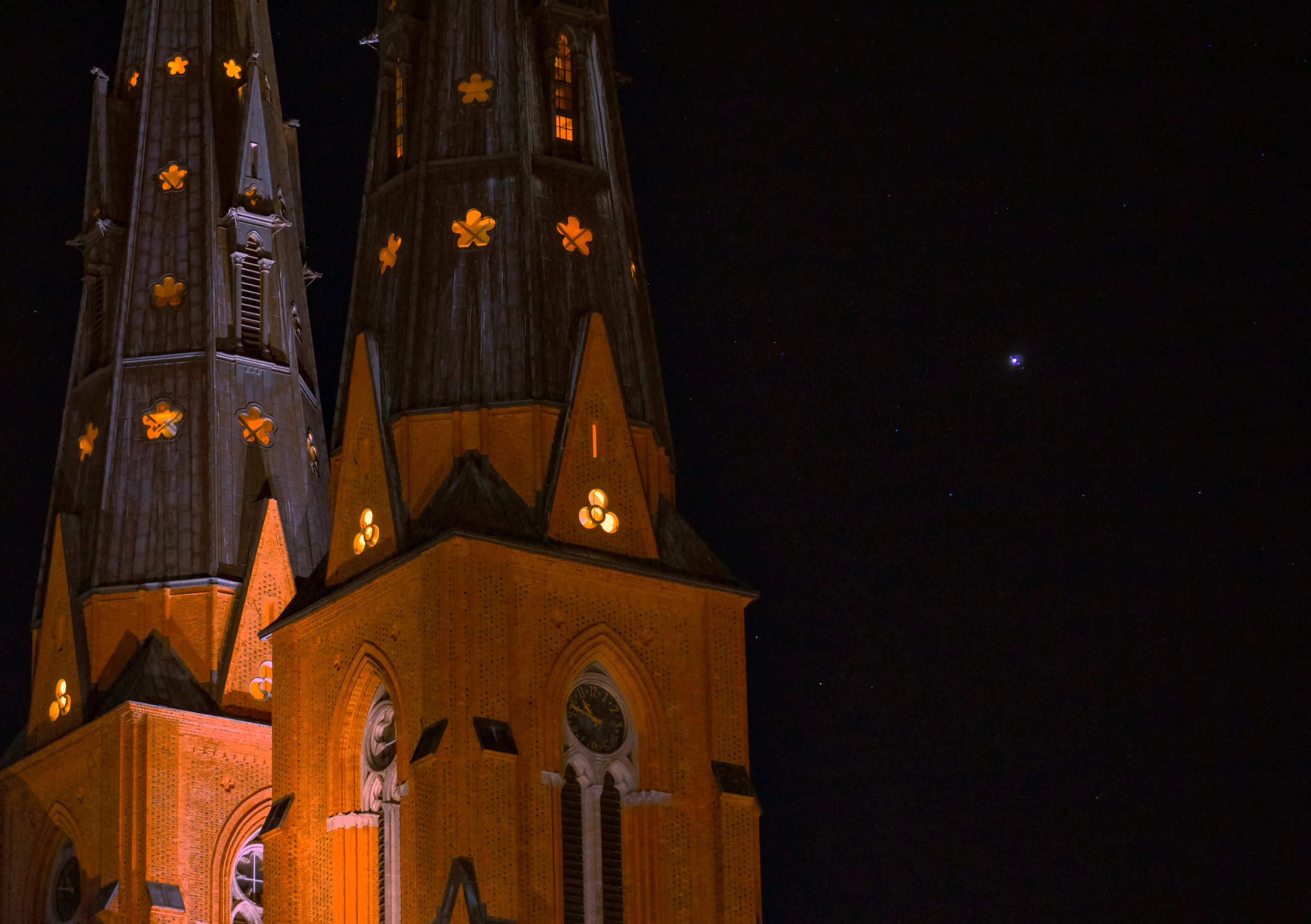 A starry sky with a view of Jupiter and it's moons, against the spires of Uppsala Cathedral.