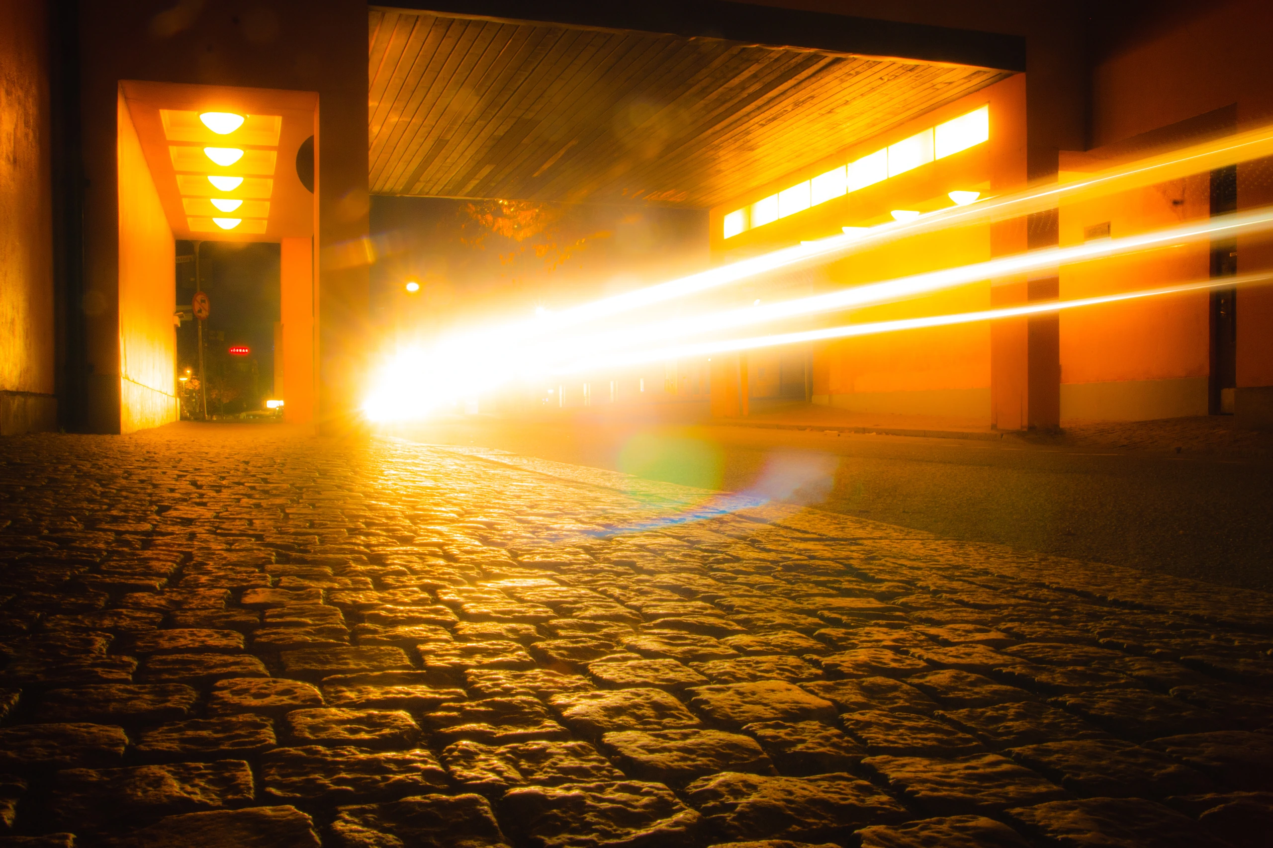 A long exposure shot of a car's light trail passing by a pavement in Uppsala.