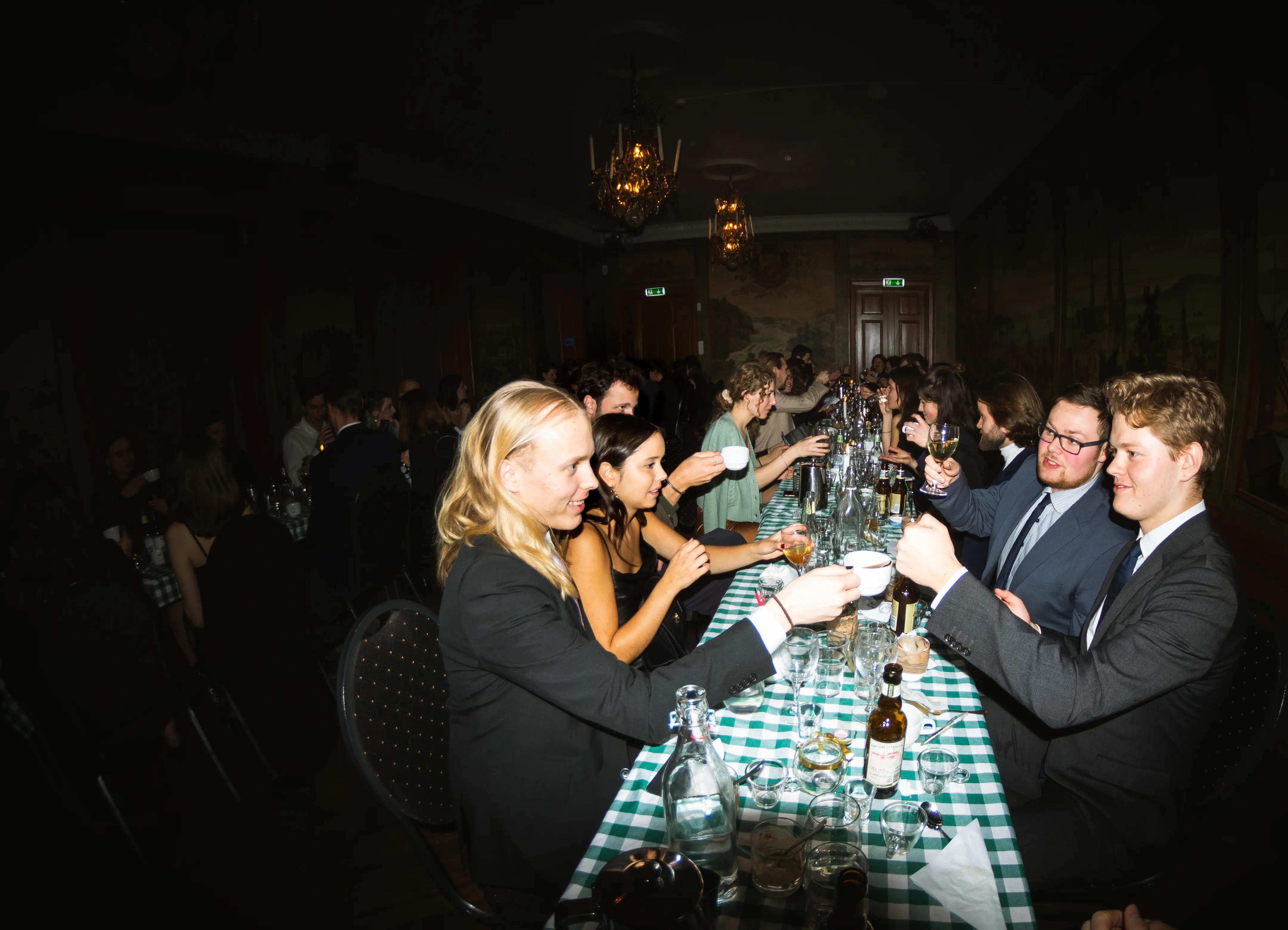 A group of people cheering each other at a gask in Västgöta Nation