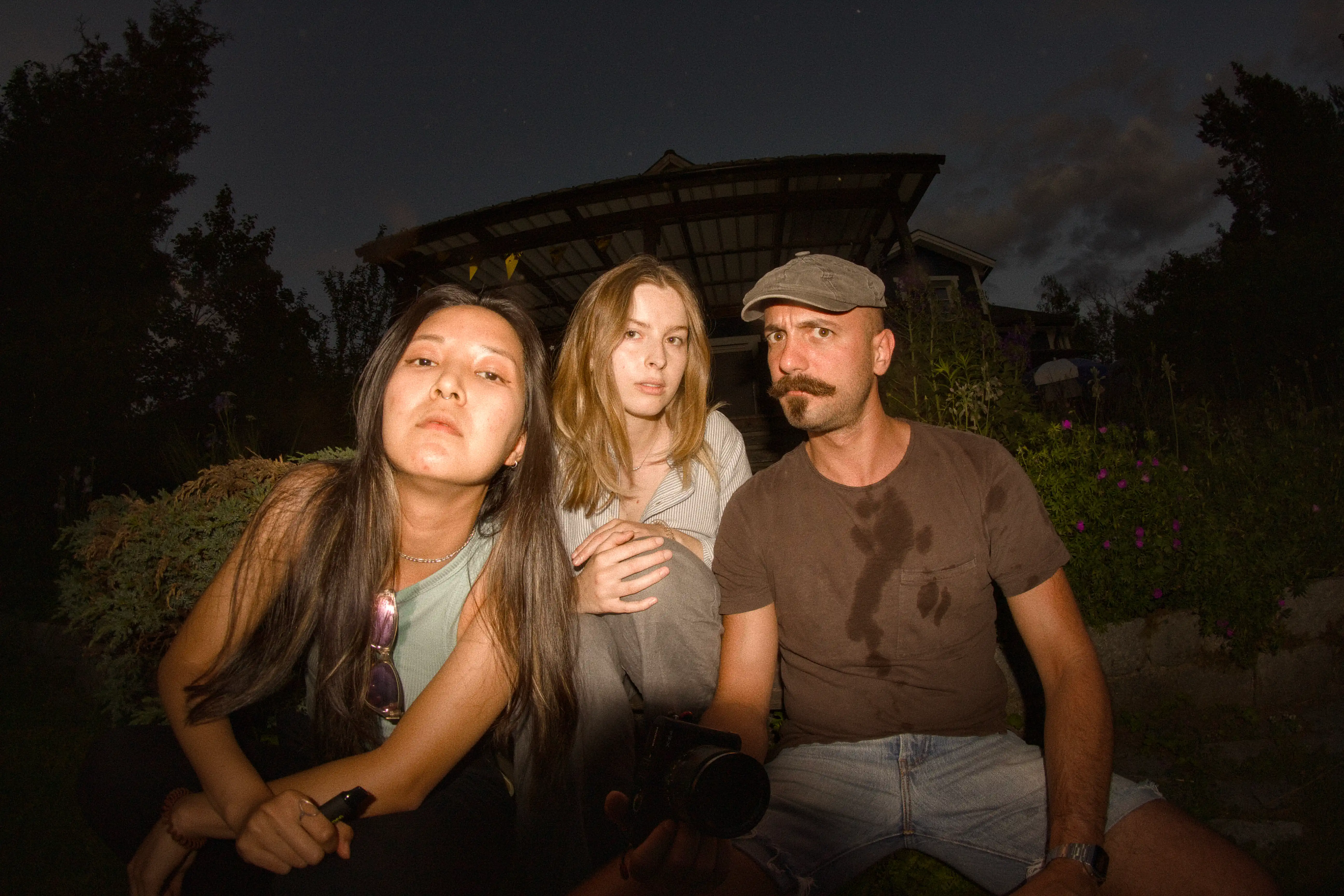 Three people posing for a photo while looking right into the camera lens during a Midsommar celebration
