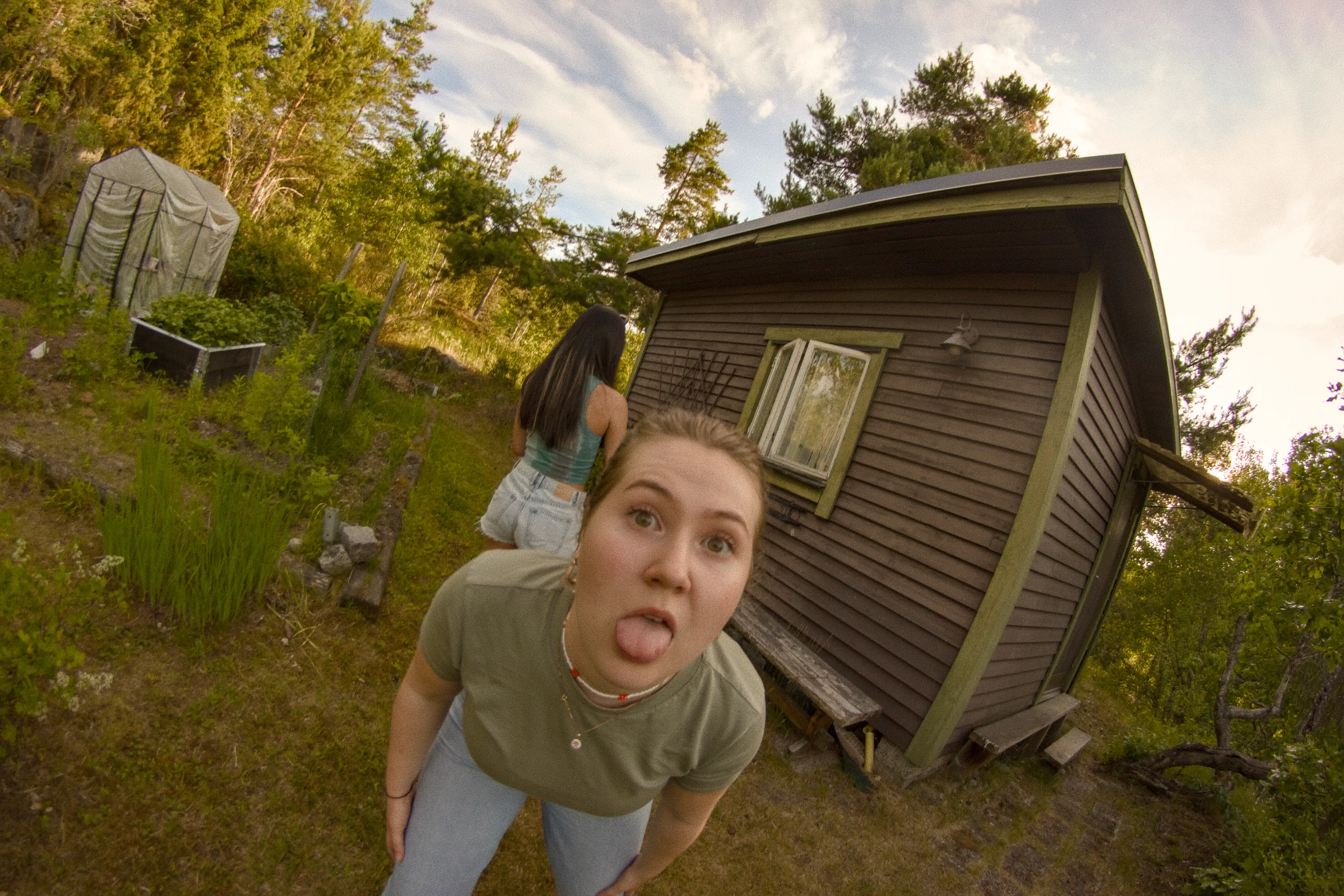A wide shot of a woman posing with her tongue out for the camera, at a Midsommar celebration.