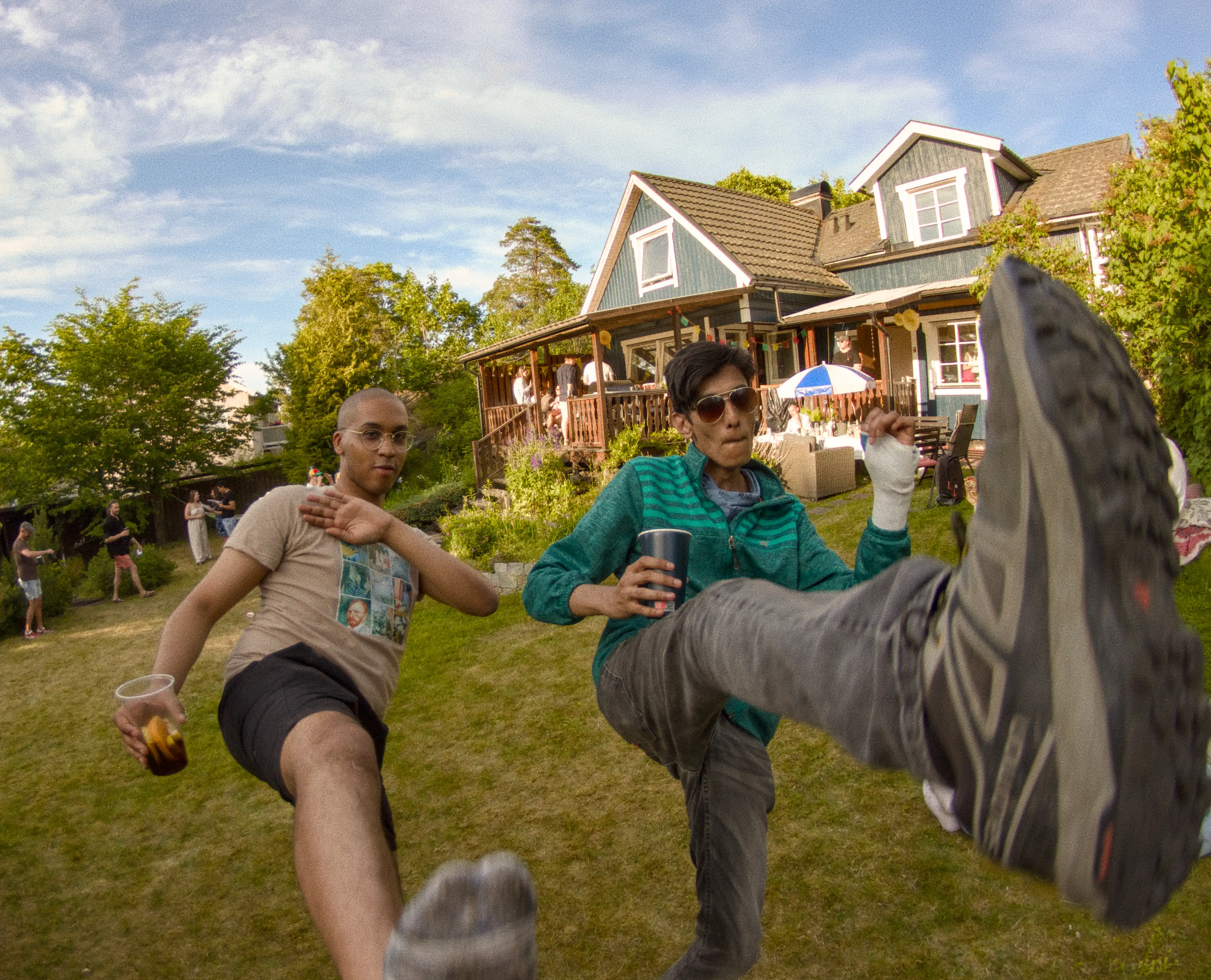 Two men kicking at the camera for a photo, during a Midsommar celebration