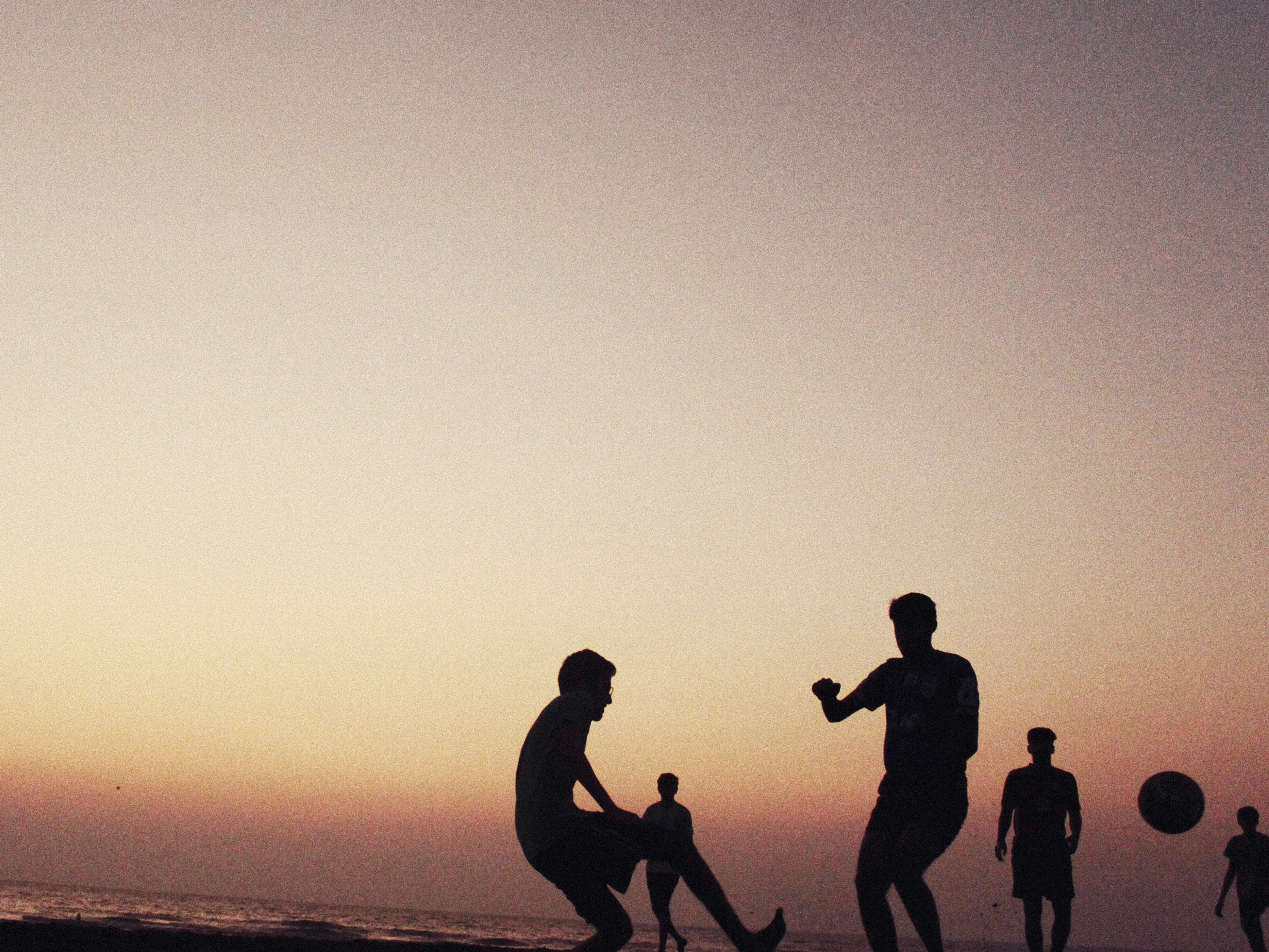 Silhouettes of boys playing football on Suruchi Beach, Mumbai