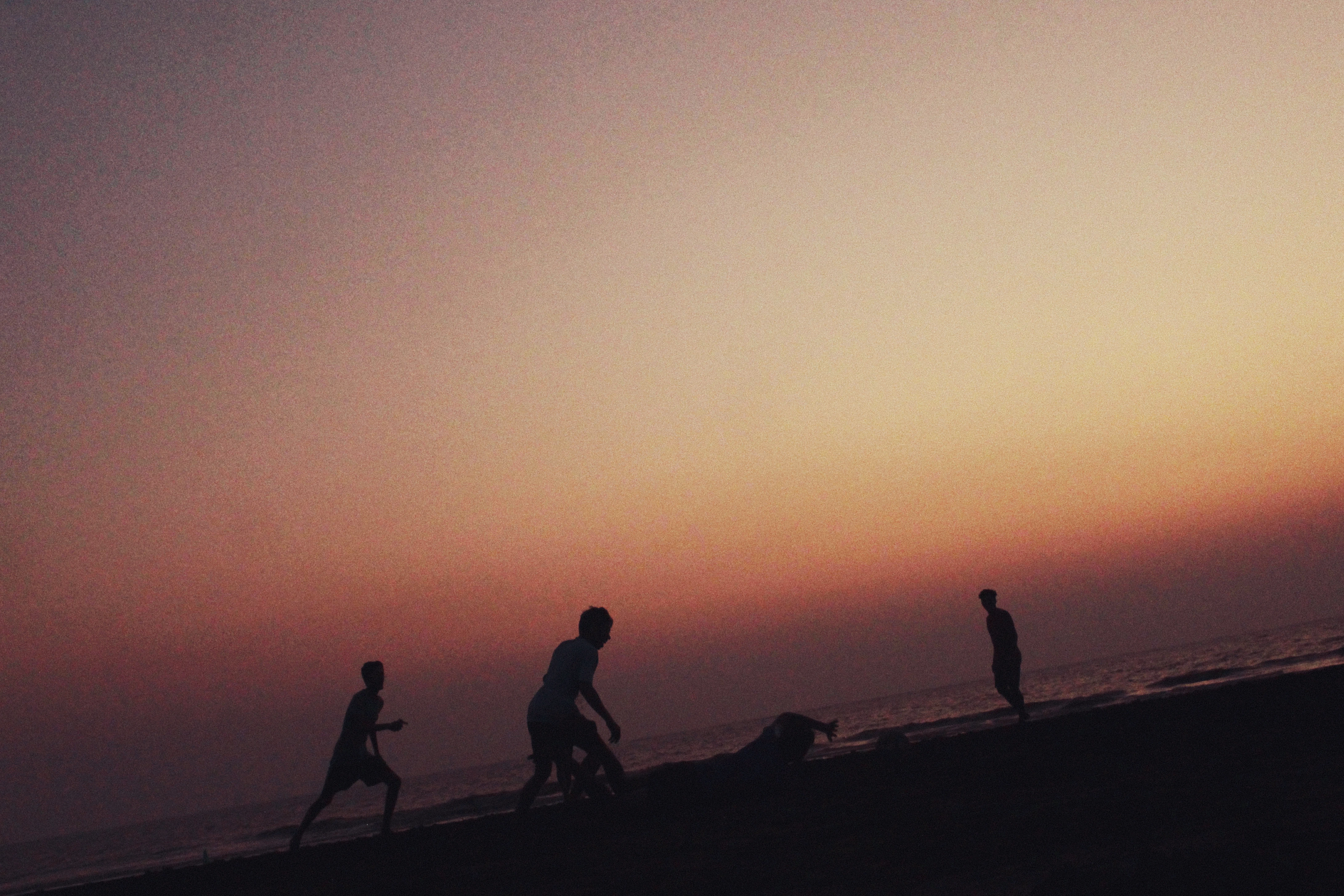 Silhouettes of boys playing football on Suruchi Beach, Mumbai