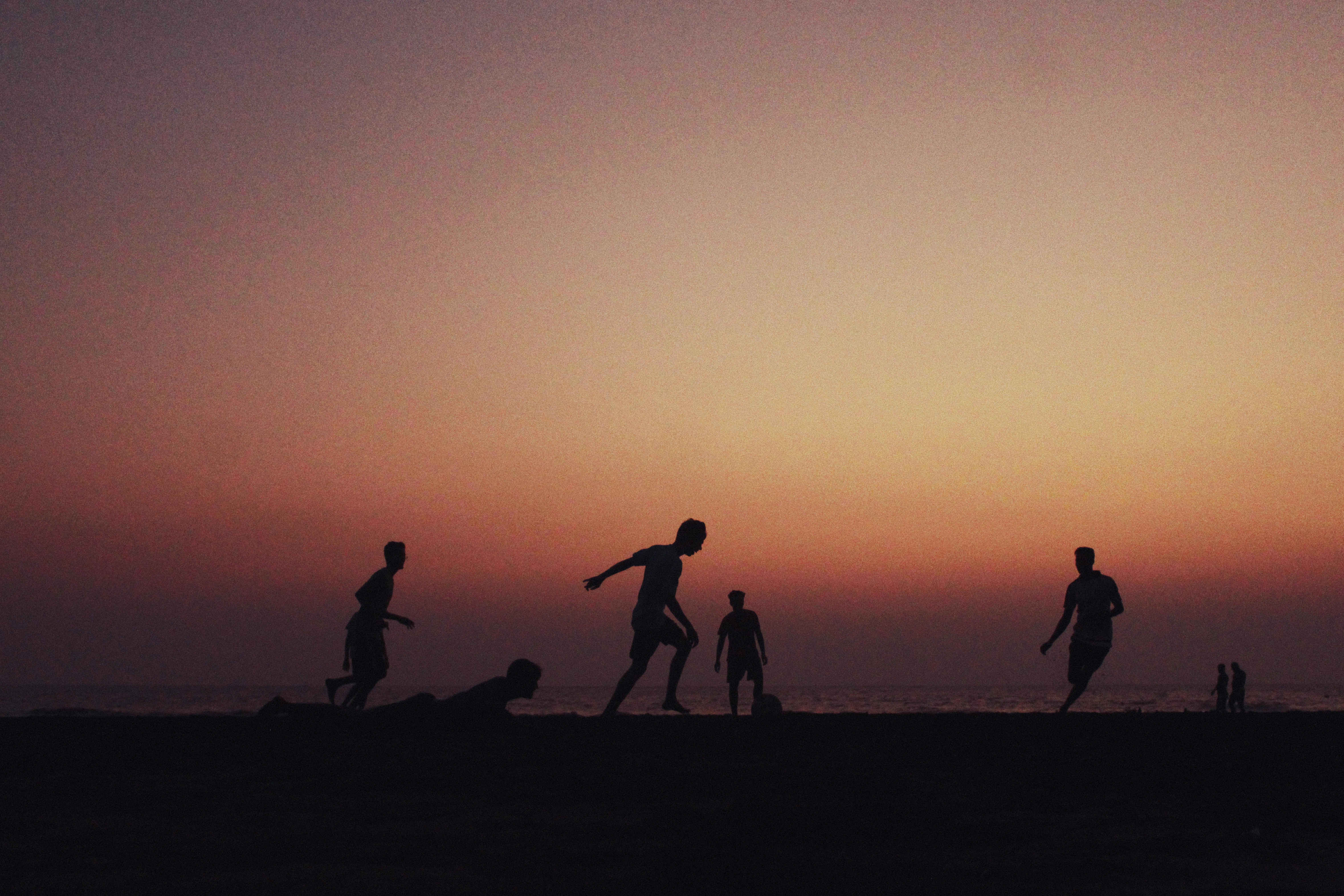 Silhouettes of boys playing football on Suruchi Beach, Mumbai