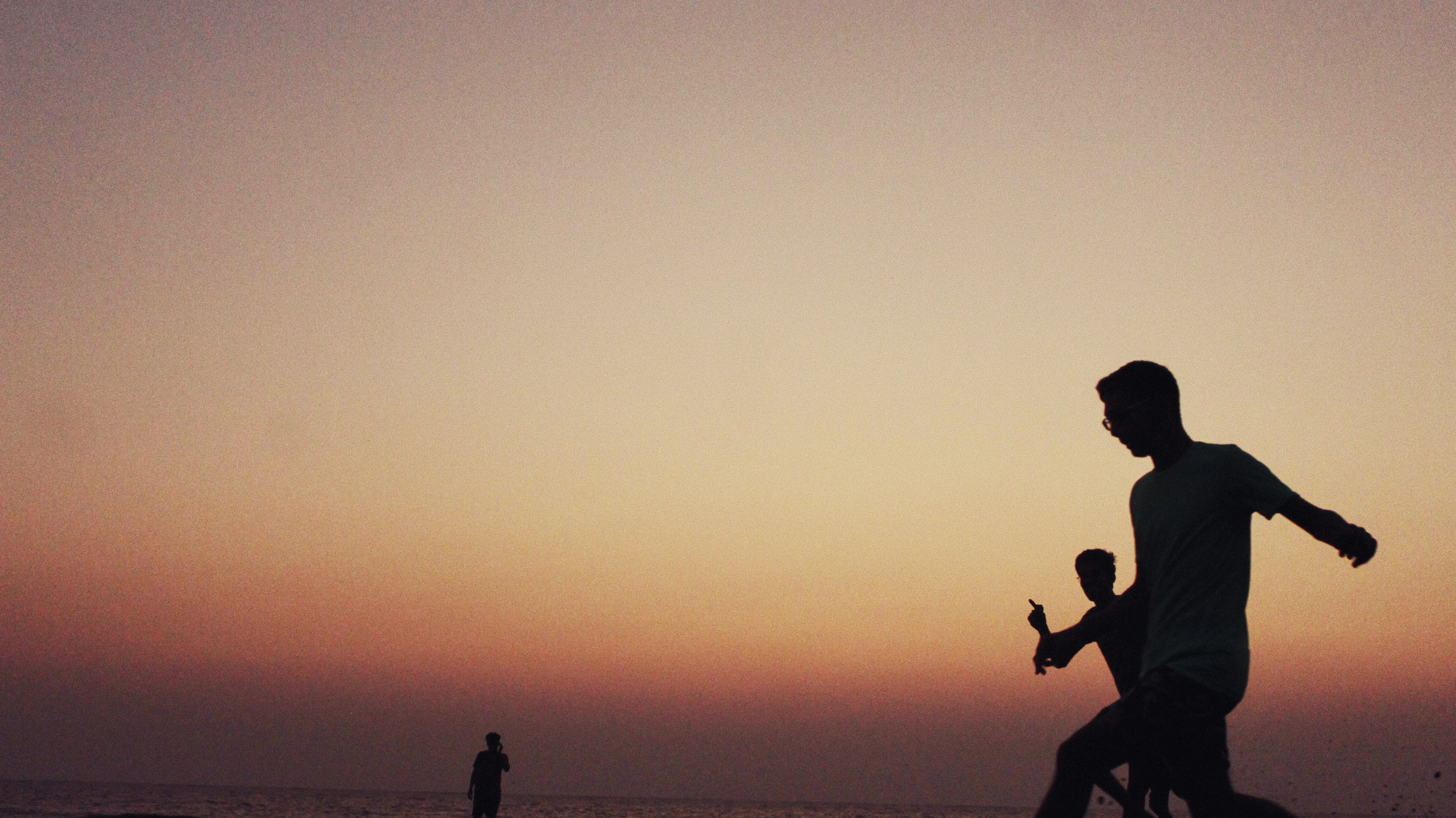Silhouettes of boys playing football on Suruchi Beach, Mumbai