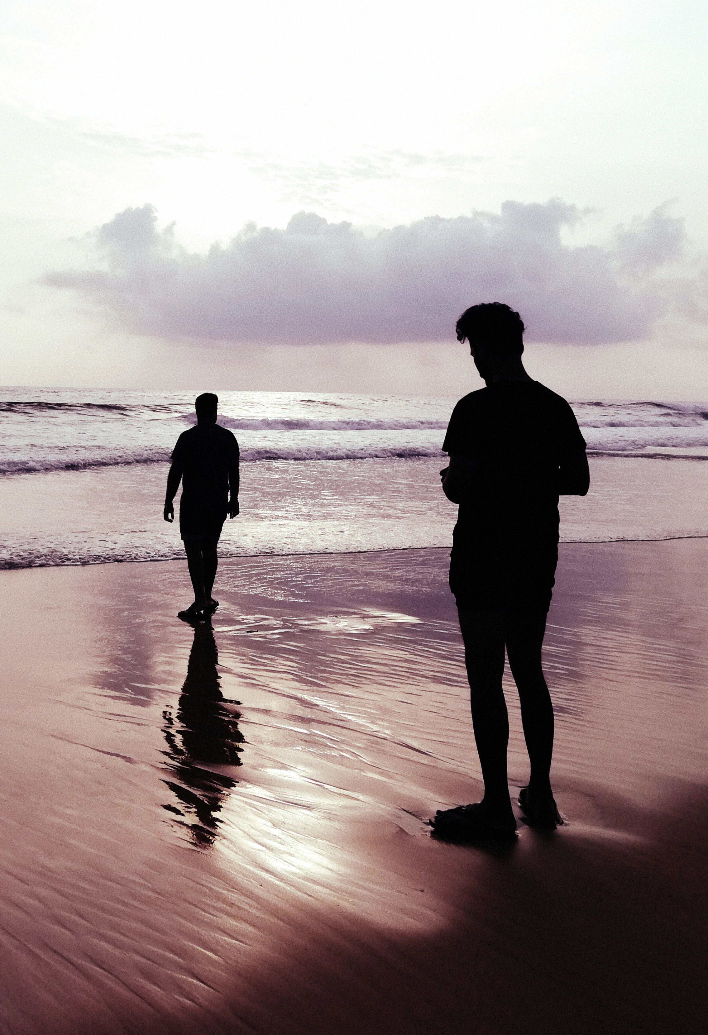 Silhouettes of two men standing at a beach in Goa