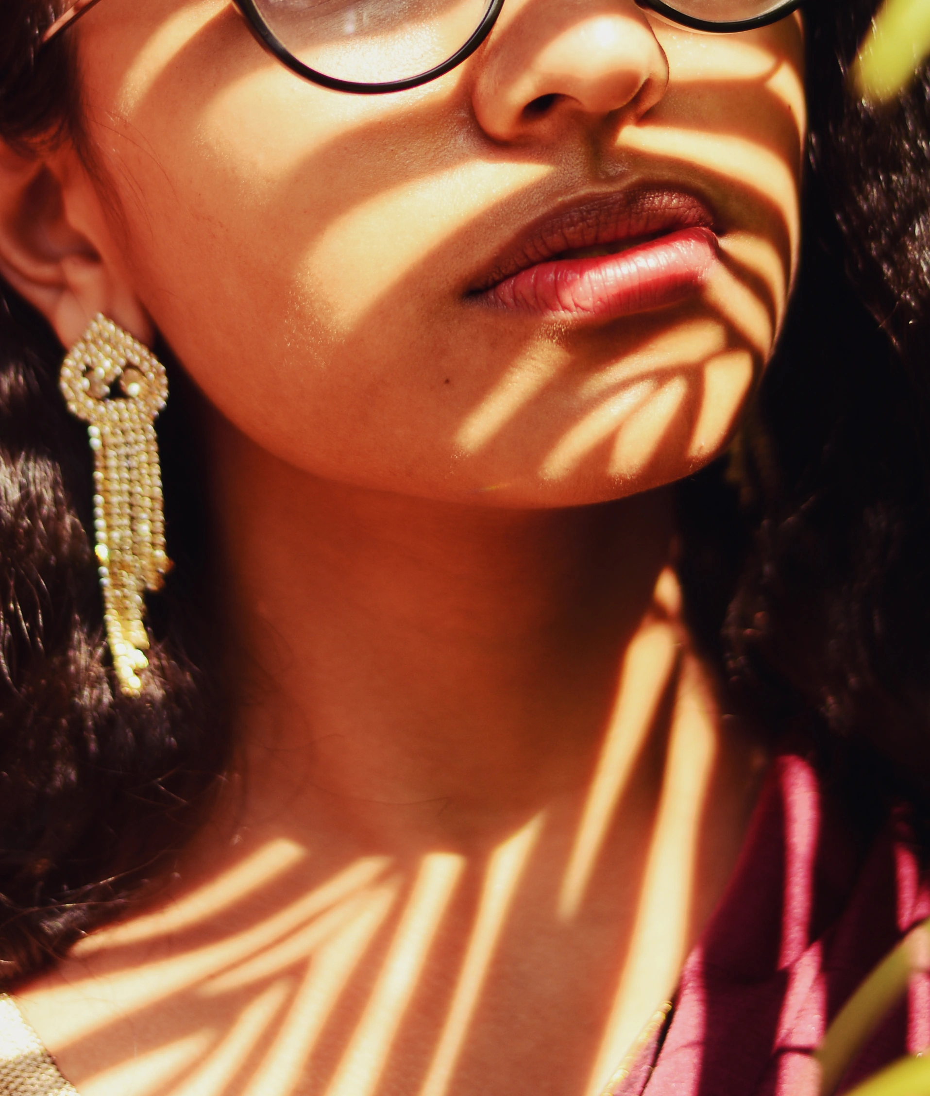 The lips of a woman, with the shadows of palm leaves projected on her face