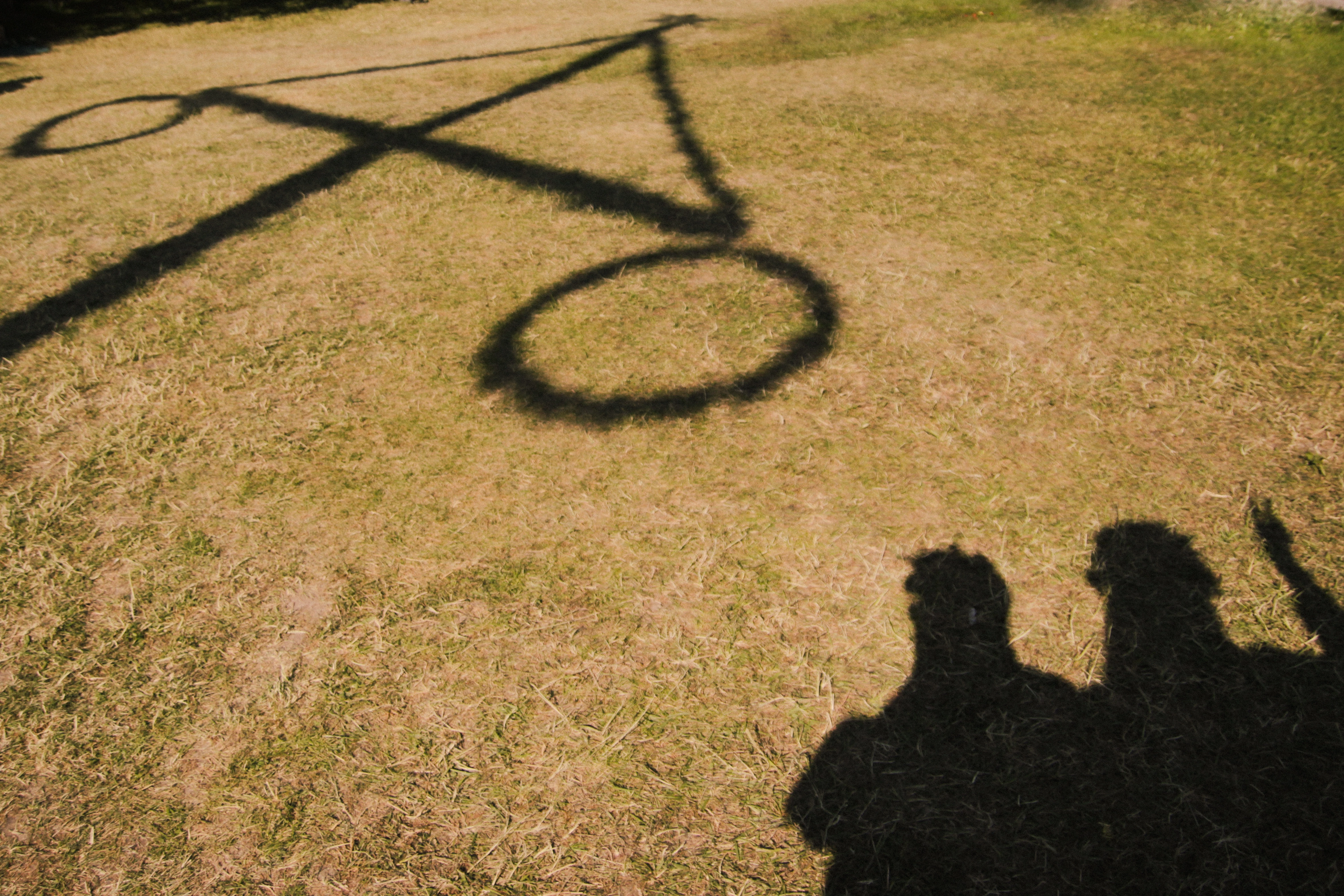 Shadows of me and my friend and a Maypole on the ground, at a Midsummer celebration in Sweden
